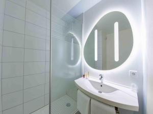 a white bathroom with a sink and a mirror at ibis budget Montpellier Sud Près d'Arènes in Montpellier +51 photos