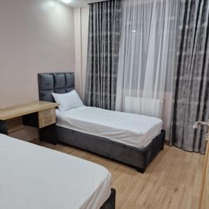'Aïn TayaにあるCozy appartement VUE SUR MER à ain taya algerのベッド2台、デスク、カーテンが備わる客室です。