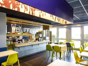 a dining room with tables and yellow chairs at ibis budget Quimper in Quimper