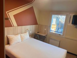 een slaapkamer met een wit bed en een raam bij ibis budget Honfleur Centre in Honfleur
