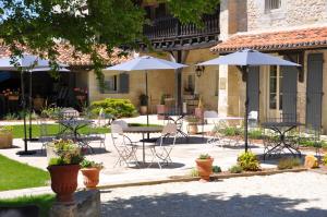 an outdoor patio with tables and chairs and umbrellas at Le Mas Des Bories - Grand Perigueux in Antonne-et-Trigonant