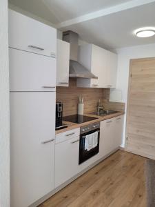 a kitchen with white cabinets and a sink at Apartament Zaharia Ötztal in Tumpen