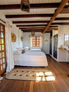 a bedroom with a large white bed and a wooden floor at Pousada Villa del Lótus in Itarema