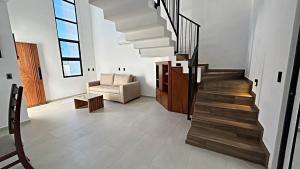 a living room with a staircase and a chair at Brand New Cow House Aldea Hortus 136 by Kivoya in Naranjo