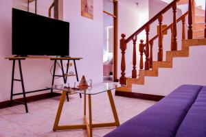 a living room with a tv on a table and stairs at Casa en la ciudad de Piura con aire acondicionado in Piura