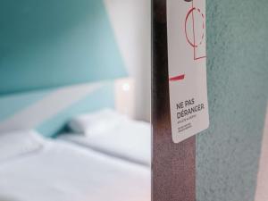 un cartel en una pared al lado de una cama en ibis Budget Mâcon Sud, en Mâcon