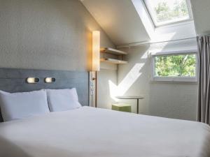 a bedroom with a large white bed and a window at ibis budget Senlis in Senlis