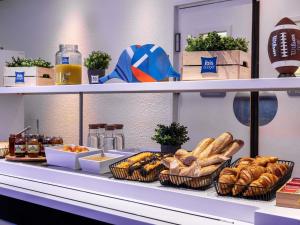 a buffet line with baskets of bread and other foods at Hotel Ibis Budget Abbeville in Abbeville