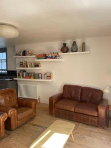 a living room with two leather couches and a table at Bright spacious flat in the heart of town in Falmouth