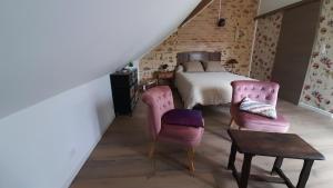 a bedroom with a bed and two pink chairs at La Maréchalerie, studio authentique au cœur d'un beau village Gâtinais 