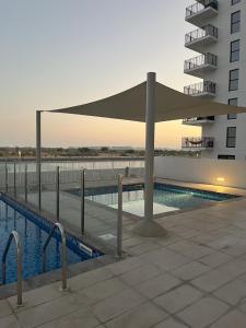 a swimming pool with a canopy next to a building at Waterfront Heaven Studio Yas Island in Abu Dhabi