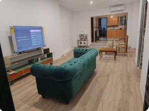 sala de estar con sofá verde y TV de pantalla plana en Villa Hogar Espartinas, en Espartinas