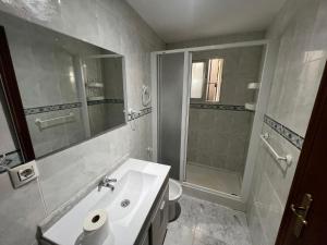 Un baño blanco con lavabo y ducha en Villa Hogar Espartinas, en Espartinas