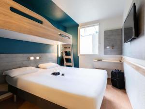 een slaapkamer met een groot wit bed en een televisie bij ibis budget Reims Thillois in Reims