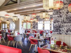 a dining room with tables and chairs and chandeliers at ibis budget Bayonne in Bayonne