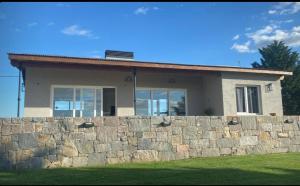 a house behind a stone retaining wall at PIUKE lugar de descanso in Tandil