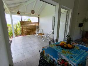 a room with a table and chairs and a patio at Gites kaz à klemence - bungalow indigo in Anse-Bertrand
