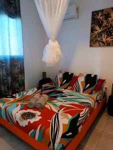 a bedroom with a bed with a colorful comforter at Gites kaz à klemence - bungalow indigo in Anse-Bertrand