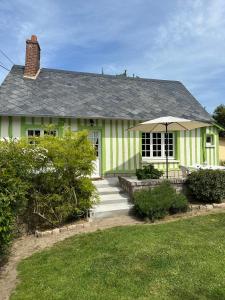 a green and white house with an umbrella at Gîte la Floria in Sotteville-sur-Mer