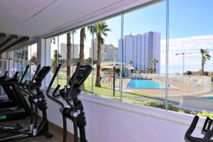 una palestra con vista sulla piscina e sulle palme di Sunset Waves I by Terreta Rentals a Benidorm