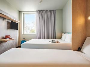 a hotel room with two beds and a window at Ibis budget Brest Sud Plougastel - Hôtel rénové in Plougastel-Daoulas