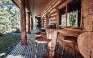 Una cabaña de madera con taburetes en una terraza. en Cuan Den Log Cabin, en Mount Buller