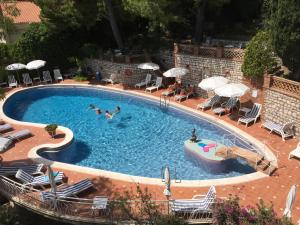 a pool with people swimming in it with chairs and umbrellas at Hotel Mediterranée in Taormina