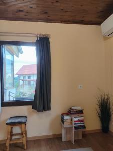 una stanza con una finestra, una sedia e dei libri di Вила Хармония Harmony Cottage a Zhilentsi