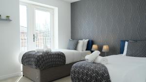 a bedroom with two beds and a couch and a window at 4 Bedroom 3 Bathroom House - Sleeps up to 8 - City Centre - Free Parking, Fast Wifi, Private Garden and Smart TV by Yoko Property in Milton Keynes