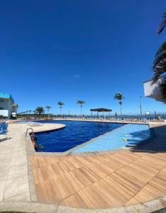 a swimming pool next to a beach with palm trees at Golden lake apartamento com linda vista para piscina in Arraial do Cabo +33 photos