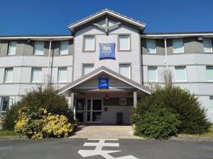 a large white building with a blue sign on it at ibis budget Granville in Granville