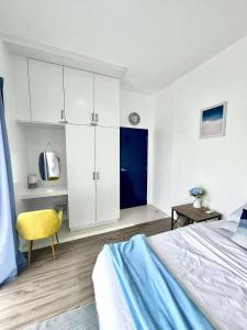 a white bedroom with a bed and a yellow chair at The Coastal Cove - One Bedroom in Iloilo City +29 photos