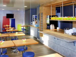 a restaurant with wooden tables and blue chairs at ibis budget Flers Grands Champs in Flers