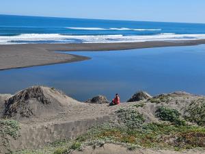 a person sitting on a beach near the ocean at Lodge Los Bosques in Matanzas