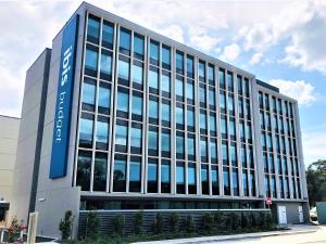 Un gran edificio de oficinas con un cartel azul. en ibis budget Sydney Airport, en Sídney
