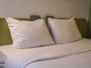 two white pillows sitting on top of a bed at Ibis Budget Bayeux in Bayeux +31 photos