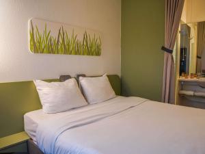 a bed with two white pillows in a room at Ibis Budget Bayeux in Bayeux