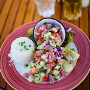 a pink plate with a salad and rice on a table at Rangiroa Maison entière privée 1 chambre 4 personnes climatisée in Ataiti