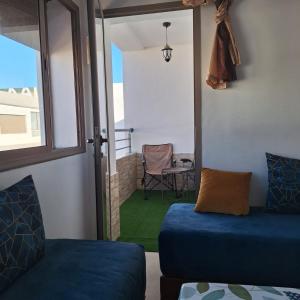 a living room with a blue couch and a chair at Malaga Beach in Mansouria +13 photos