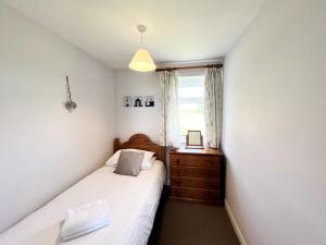 ein Schlafzimmer mit einem Bett, einer Kommode und einem Fenster in der Unterkunft Willow Apartment - Uk49303 in Woolfardisworthy
