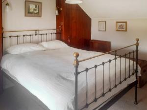 a bedroom with a large bed with white sheets at Pencaire in Helston