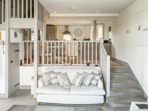 een woonkamer met een witte bank en een trap bij Woodlands View in Thorncombe