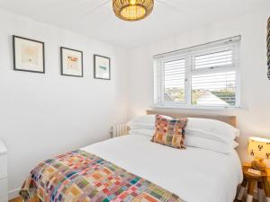 une chambre avec un lit avec des draps blancs et une fenêtre dans l'établissement Liwus, à Newquay