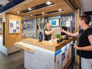 a man and a woman standing at a counter at Ibis Budget Manosque Cadarache in Manosque