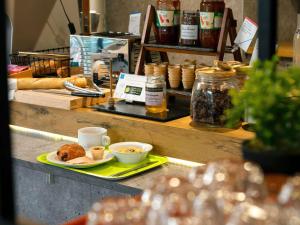 Un mostrador con un plato de comida y tazas de café. en Ibis Budget Manosque Cadarache, en Manosque