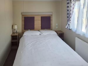 Un dormitorio con una gran cama blanca con dos ventanas. en Seaside Retreat, en South Hayling