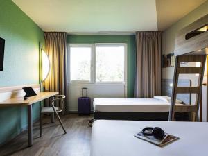 a room with two beds and a desk and a window at ibis budget Angoulême Nord in Champniers