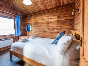 a bedroom with a large bed in a wooden wall at Tamnavulin Lodge - Uk49121 in Feshiebridge