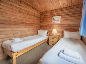two beds in a cabin with wooden walls at Tamnavulin Lodge - Uk49121 in Feshiebridge +18 photos