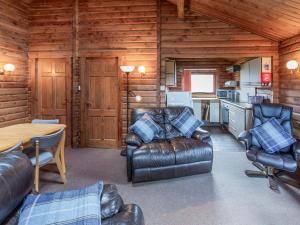 a living room with leather furniture in a log cabin at Tamnavulin Lodge - Uk49121 in Feshiebridge